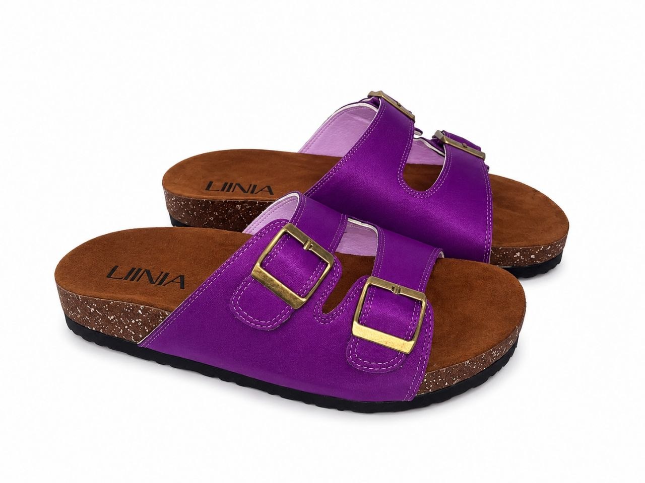 A pair of purple double-strap slide sandals with gold-tone buckles, brown cork-look midsoles, and black outsoles. The brand name 'LIINA' is printed on the footbeds.